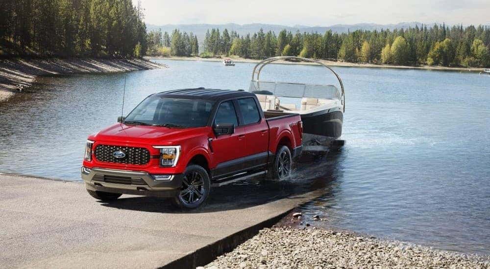 A red 2024 Ford F-150 XLT Heritage Edition is shown towing a boat near a Delaware Ford dealer.