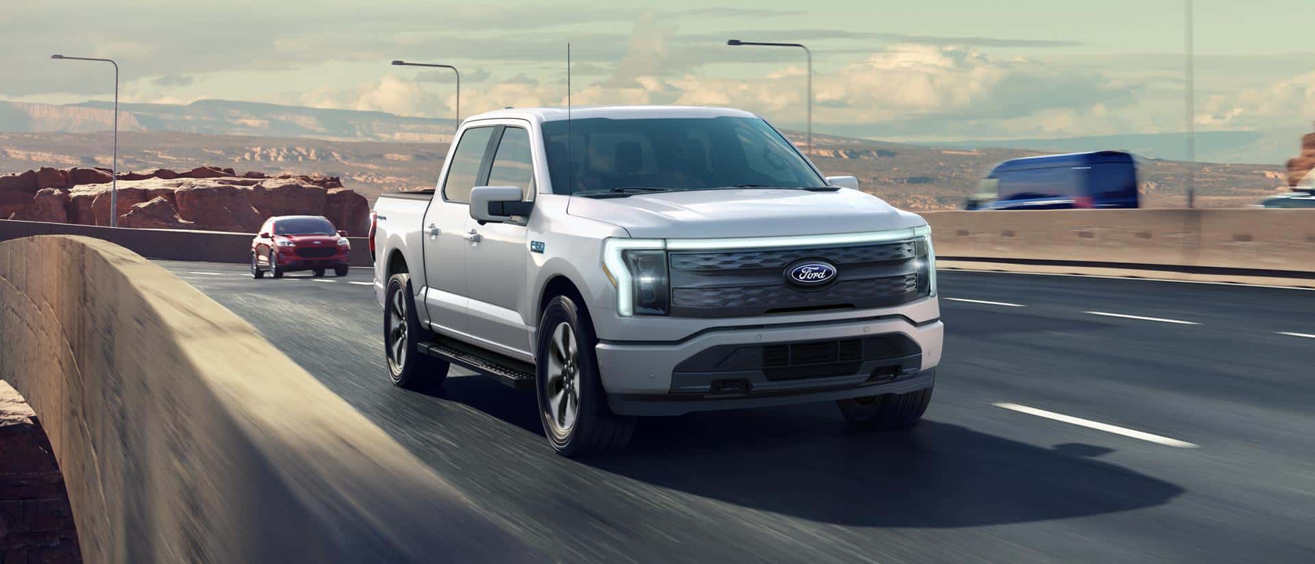 A silver Ford F-150 driving quickly over a bridge in a desert.