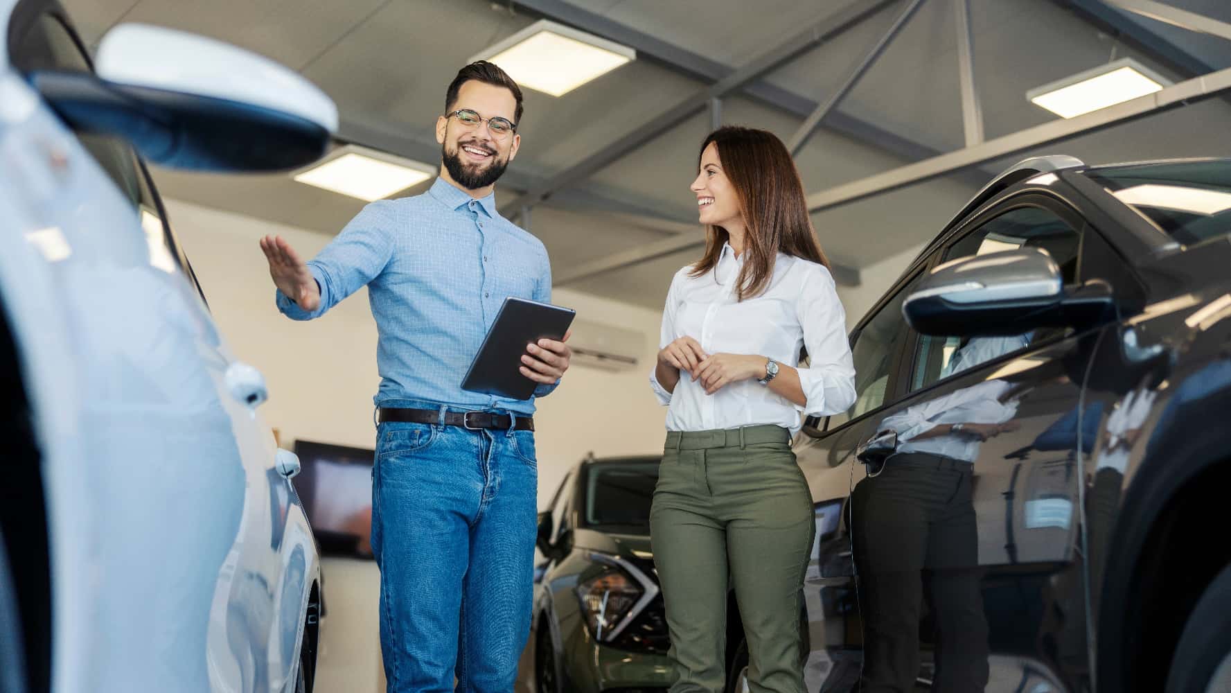 A car salesman selling a car to a woman in a dealership.