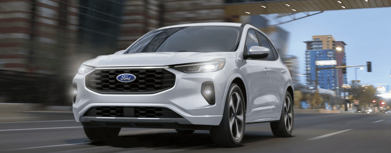 A silver Ford Escape driving through an urban area.