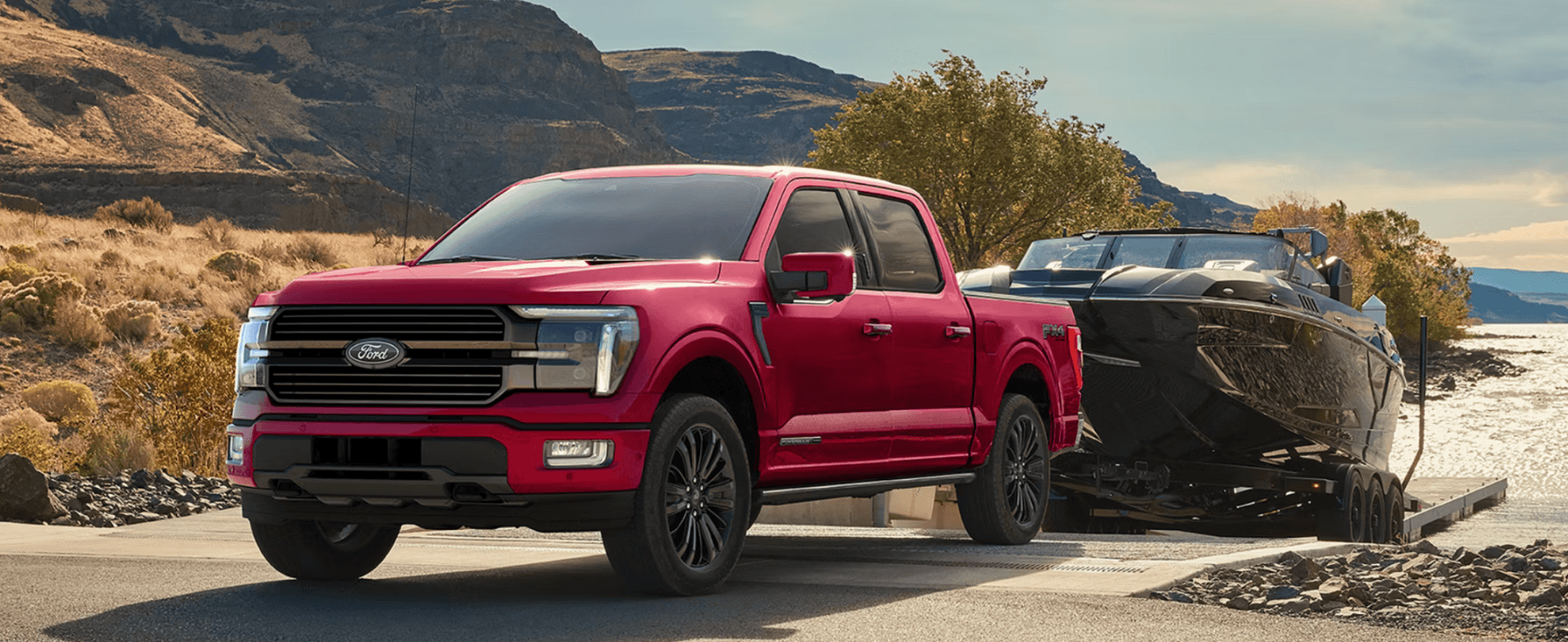 A red Ford F-150 backing a boat into a body of water.