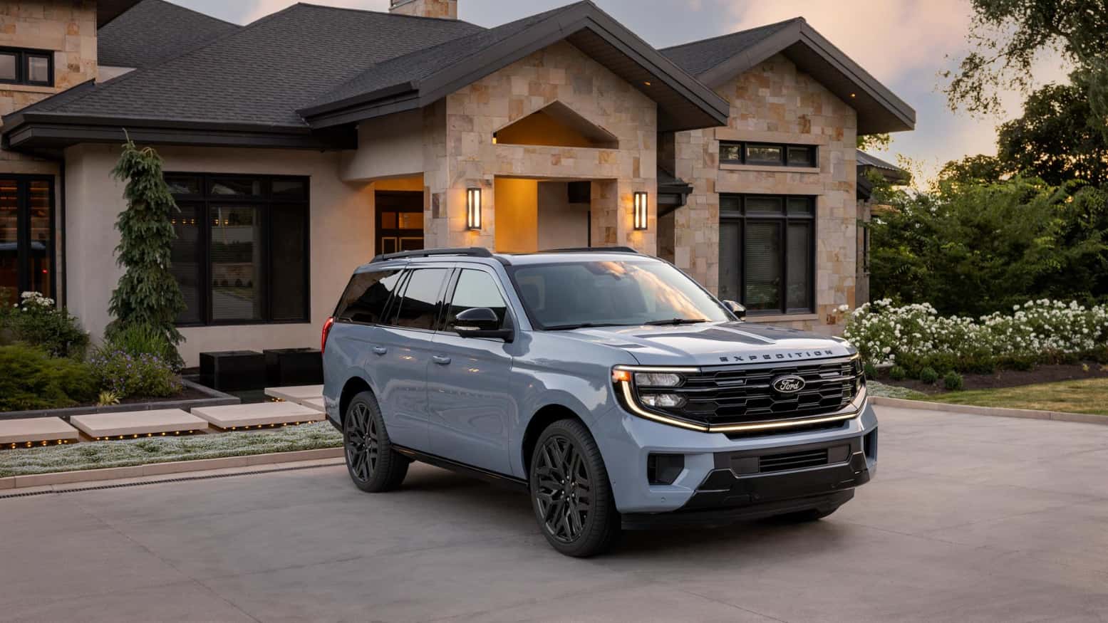 A light blue Ford Expedition parked in front of a nice house.