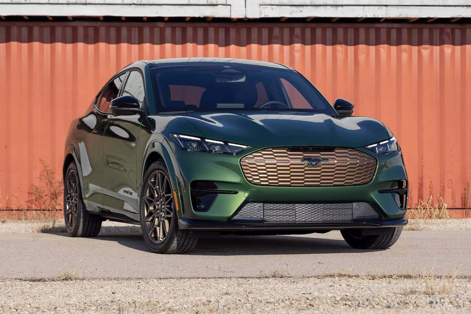 a green 2025 ford mustang mach-e parked next to a metal building