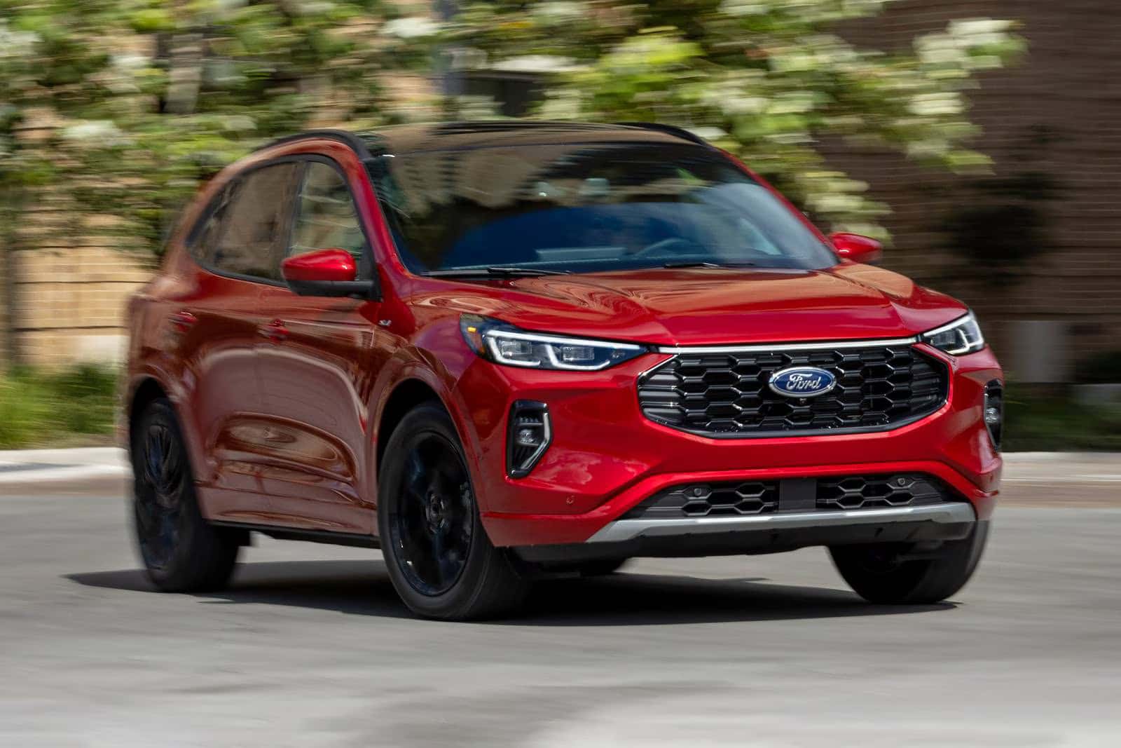 a red 2026 ford escape driving on a road in the a suburban area