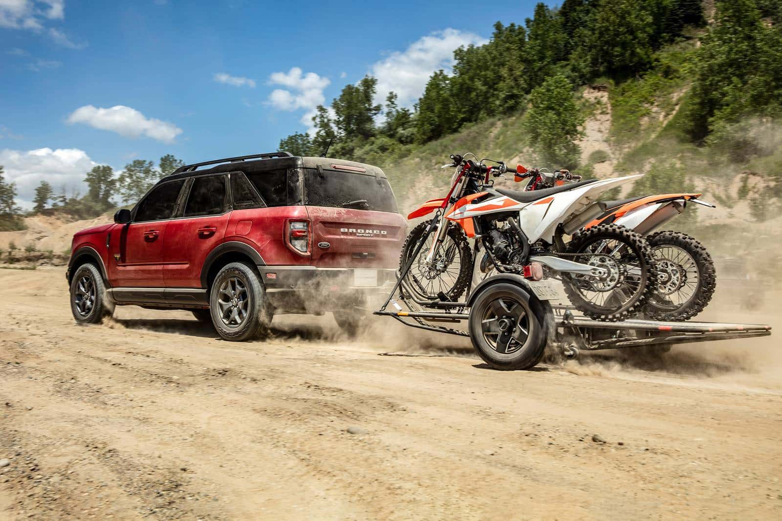 a 2026 Ford Bronco Sport driving in the desert hauling a trailer with dirt bikes on the trailer