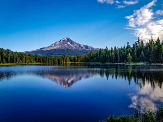 Trillium Lake in Oregon with reflection of Mt. Hood on blue water and white clouds in blue sky