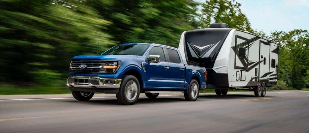 A Strong Azure 2024 Ford F-150 Pulling A Trailer On A Highway