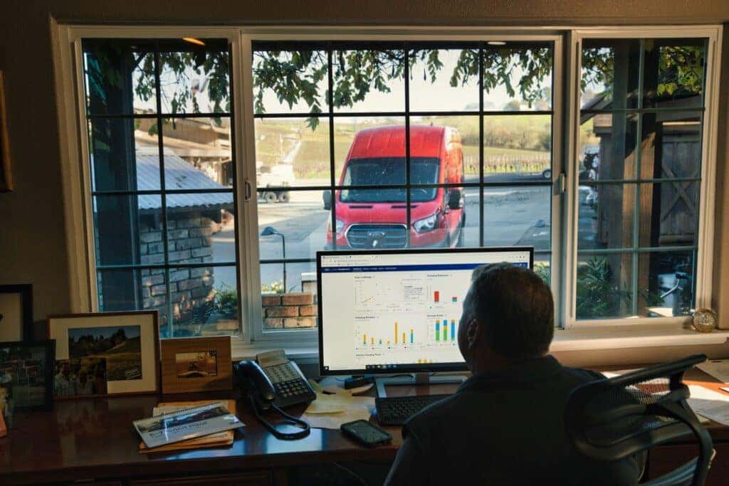 A Loyal Ford Customer Working Inside, His Ford Car Outside The Window