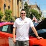diehl's finance manager, perry wayne, in front of a red dodge with the hood up, smiling for the photo
