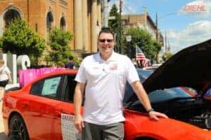 diehl's finance manager, perry wayne, in front of a red dodge with the hood up, smiling for the photo