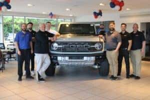 eight diehl ford of beaver staff members smiling for the camera with a light blue bronco in the middle