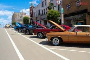 vintage cars parked on the street with hood up at the beaver car cruise