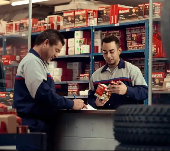Two Parts Technicians are looking over parts in the Ford Parts Center.