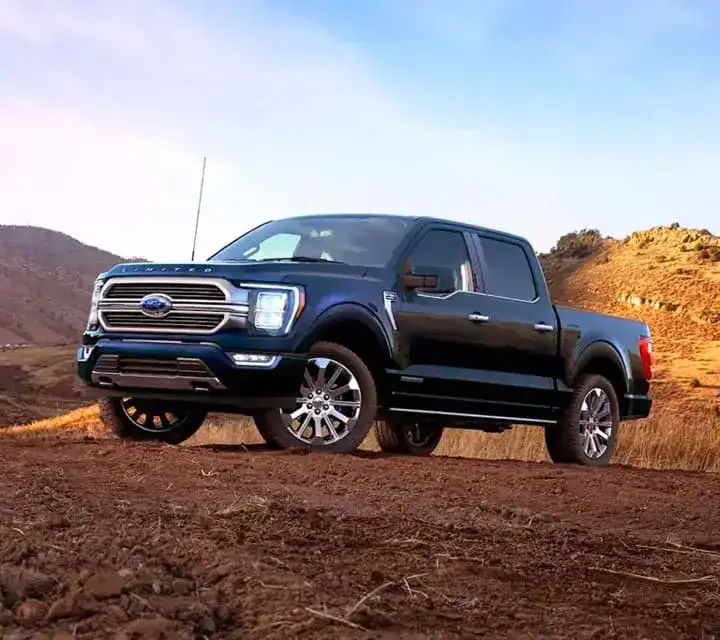 Ford truck parked on a dirt hill in the desert.