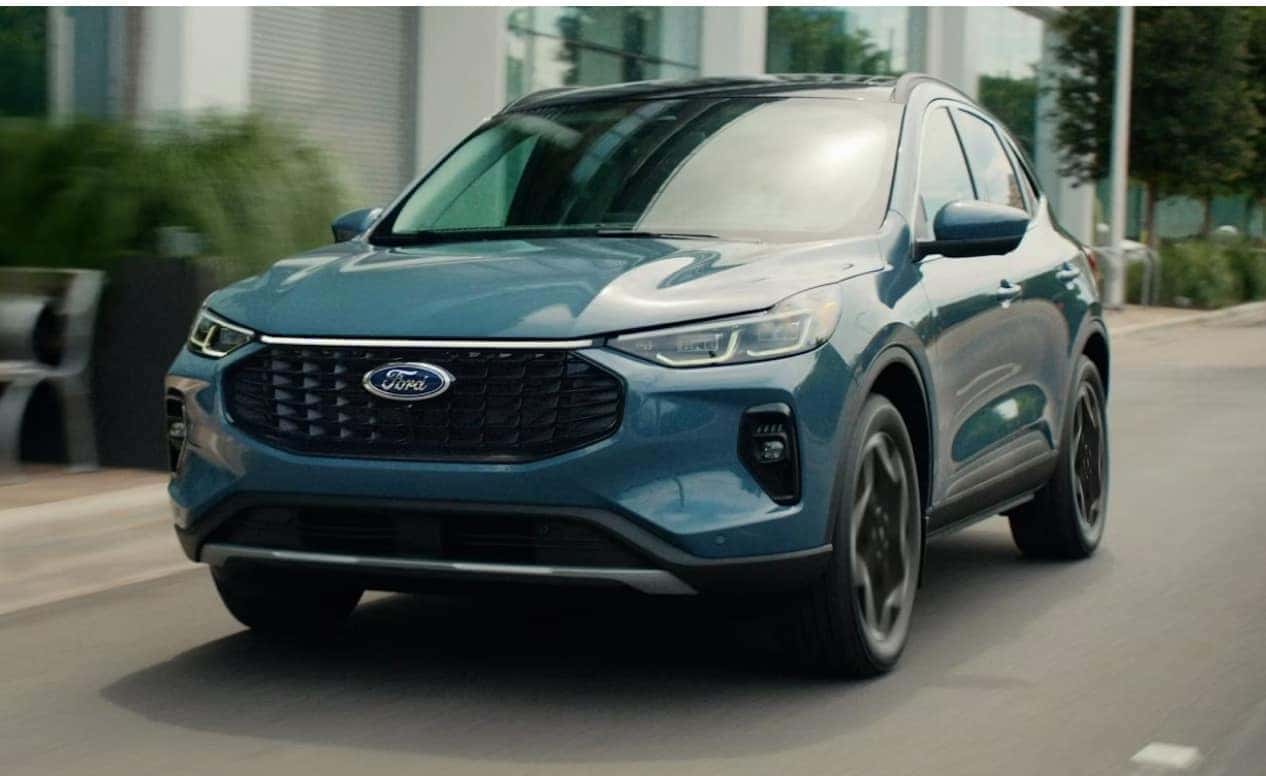A blue Ford SUV drives on a city street, showing a modern design with sleek lines and large wheels, conveying motion and urban sophistication.