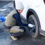 A Japanese woman changing her cars tires from normal street tires to snow studless tires at the beginning of winter.