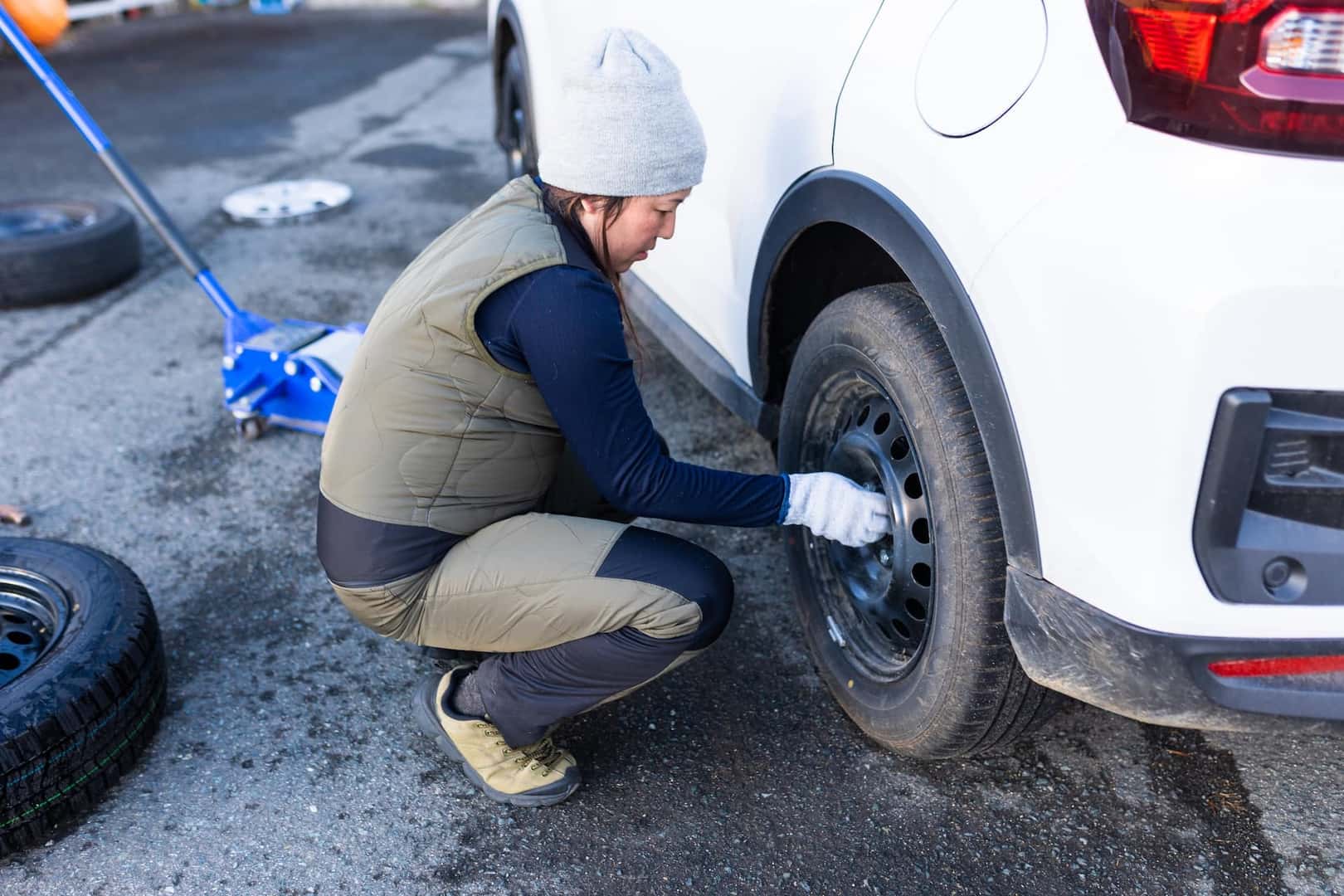 A Japanese woman changing her cars tires from normal street tires to snow studless tires at the beginning of winter.