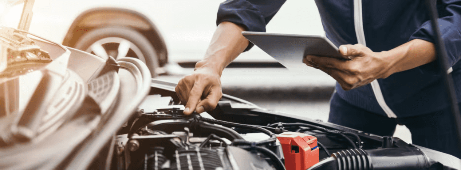 A mechanic's hands are the focus as he works on the engine of a car