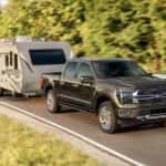A Ford F-150 towing a trailer behind it on the road.