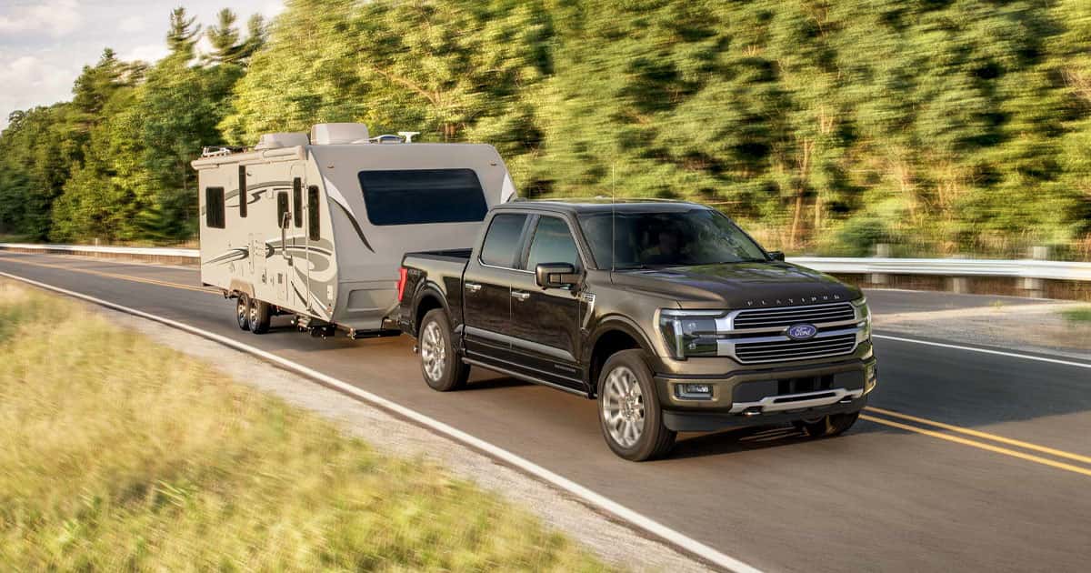 A Ford F-150 towing a trailer behind it on the road.