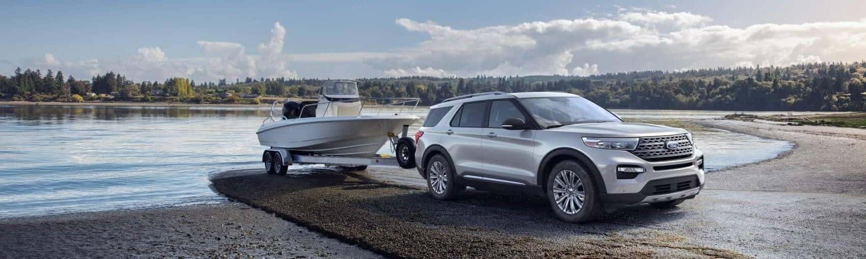 Ford Explorer with speedboat hitched parked on the shore of lake