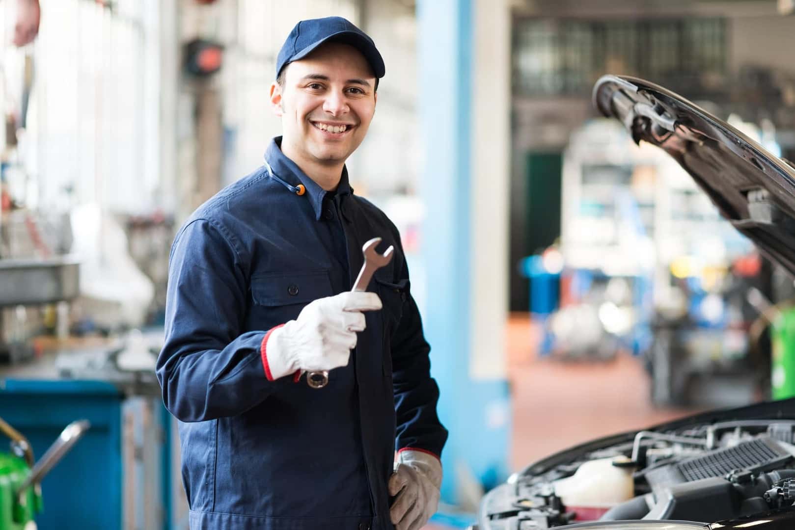 Ford Certified Technician smiling and holding up wrench while servicing a Ford vehicle at the Service Center