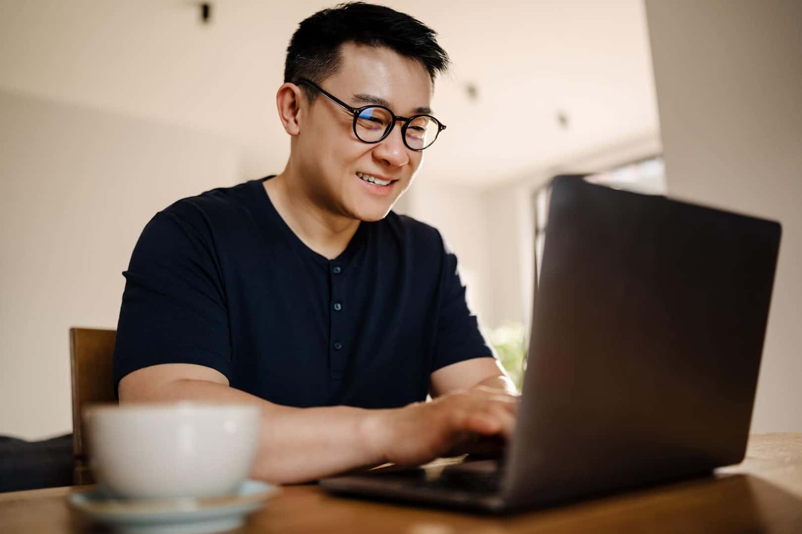 Man smiling while searching online tools on laptop
