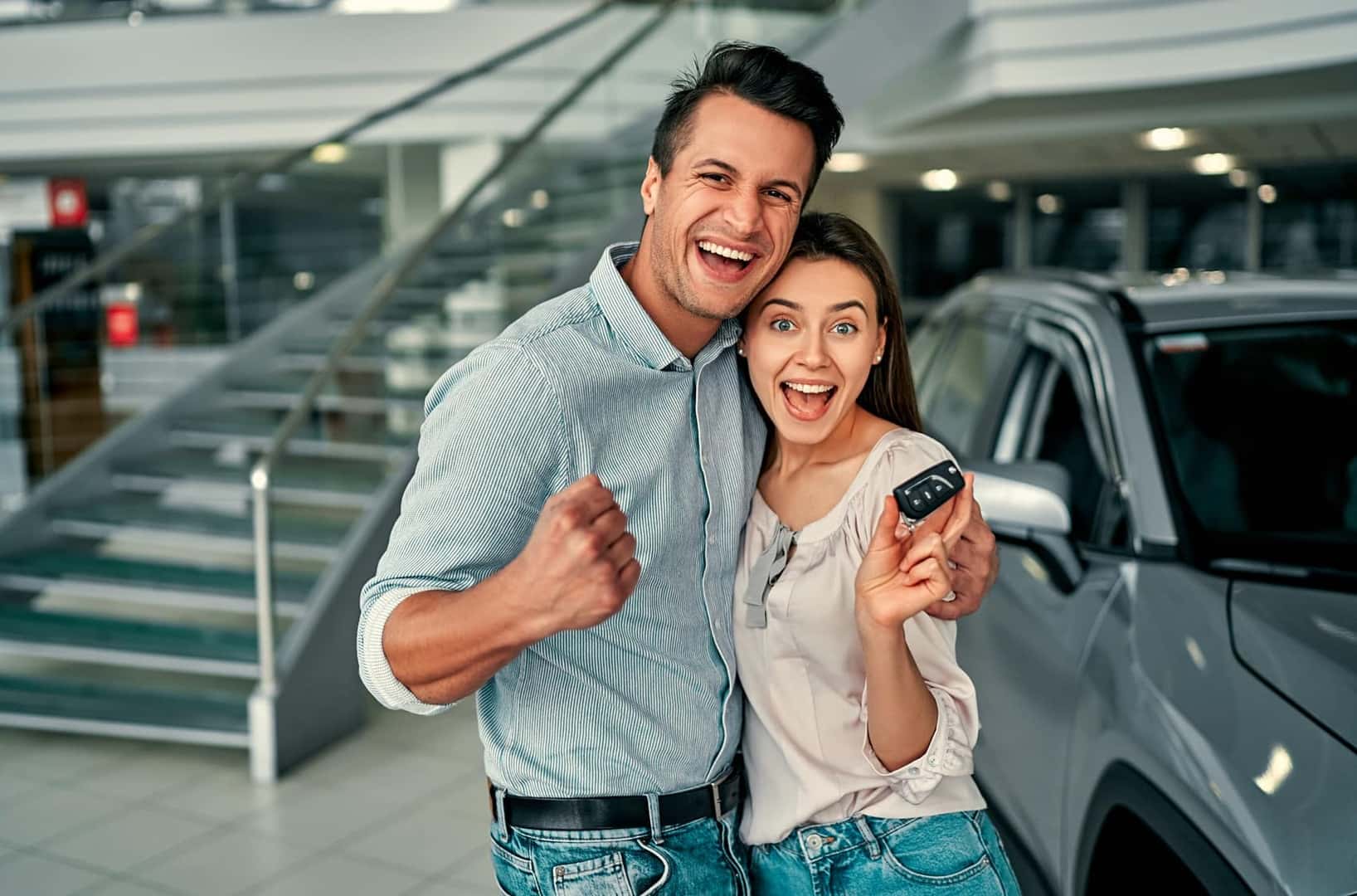 Couple smiling while holding up keys to their new Ford vehicle