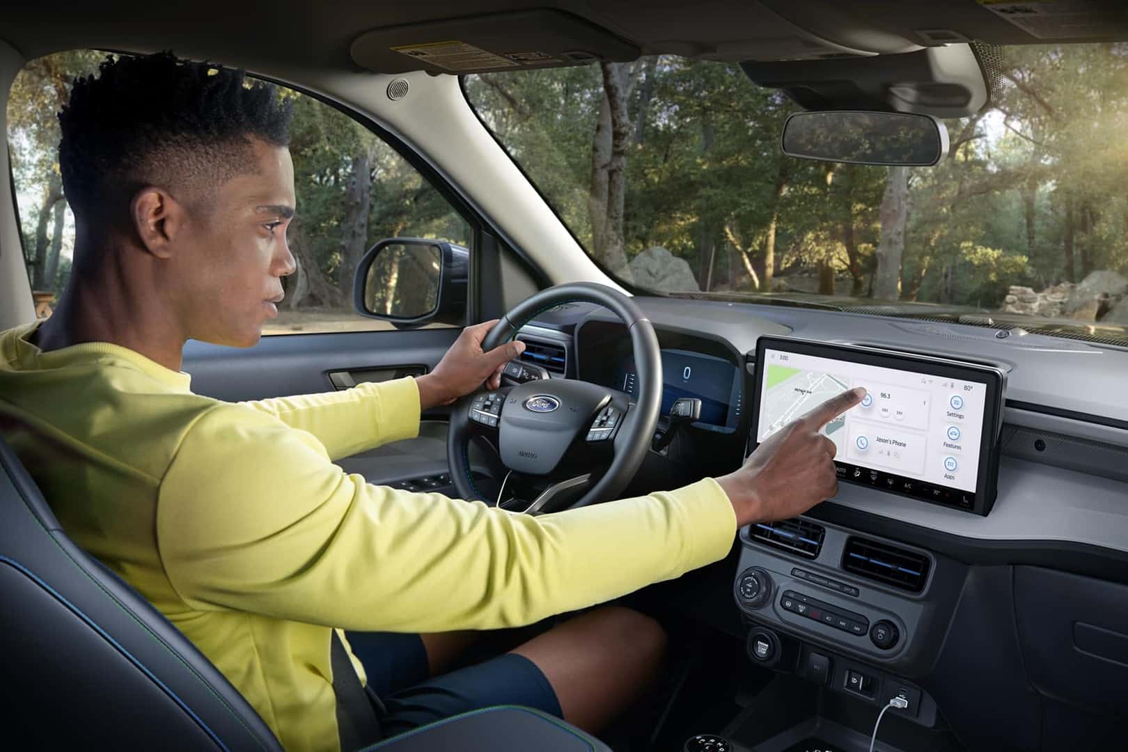 Man sitting in driver's seat of Ford Maverick setting up navigation on touch screen connected to dashboard