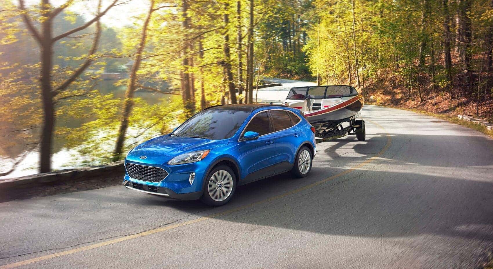 Ford Escape towing boat while driving along a lake in the woods from Ford Escape Dealership near Upland CA