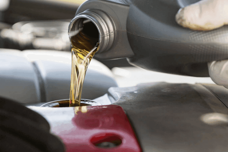 service technician pours oil in car engine - mobile
