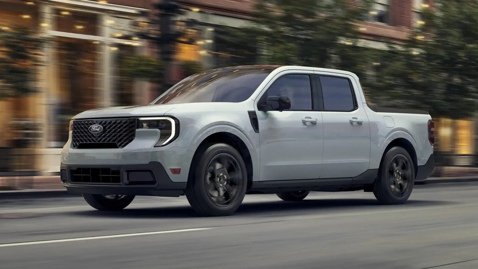 2025 Ford Maverick® driving through city street in motion, highlighting compact truck exterior styling.