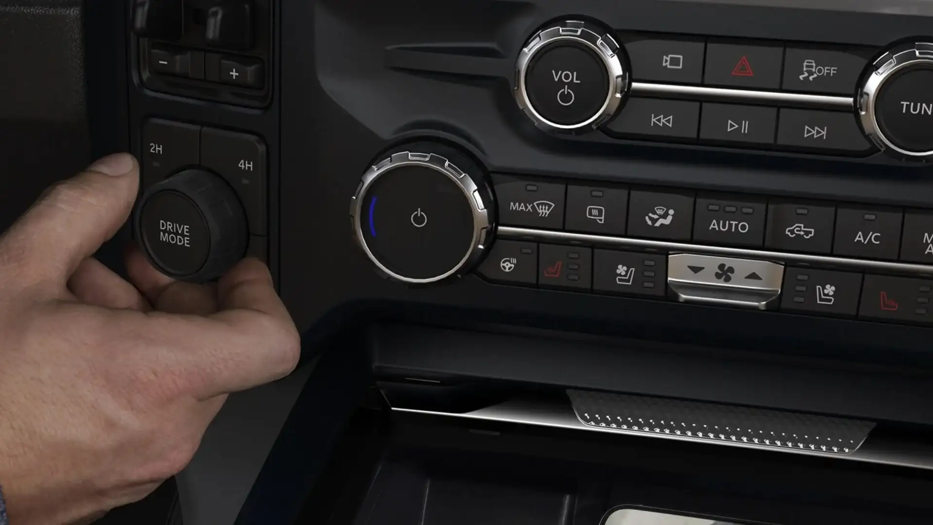 Close-up of 2026 Ford Super Duty® drive mode dial and climate control buttons with hand adjusting.