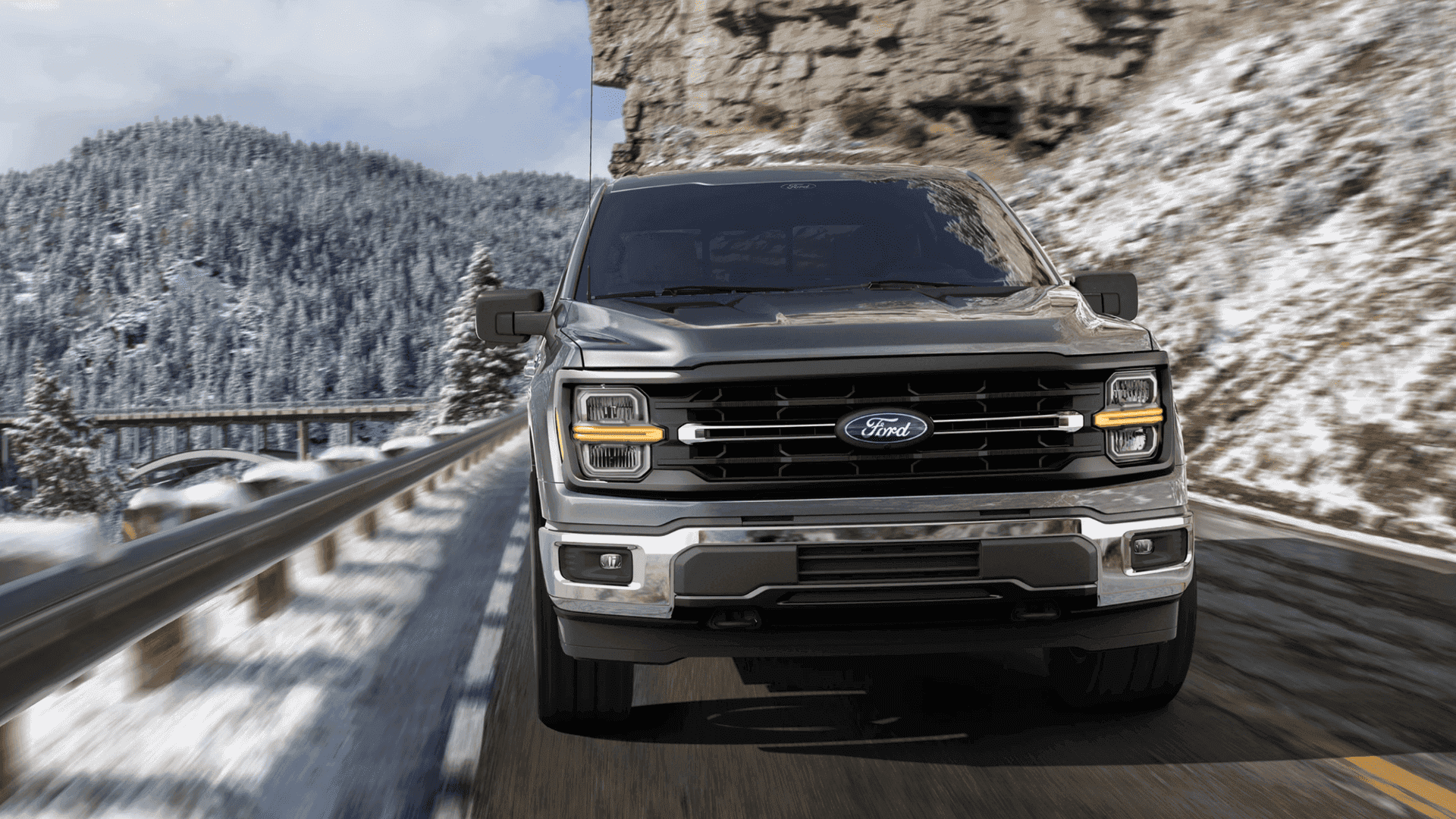 Front-facing view of a 2025 Ford F-150® truck driving through snow-covered mountain roads.