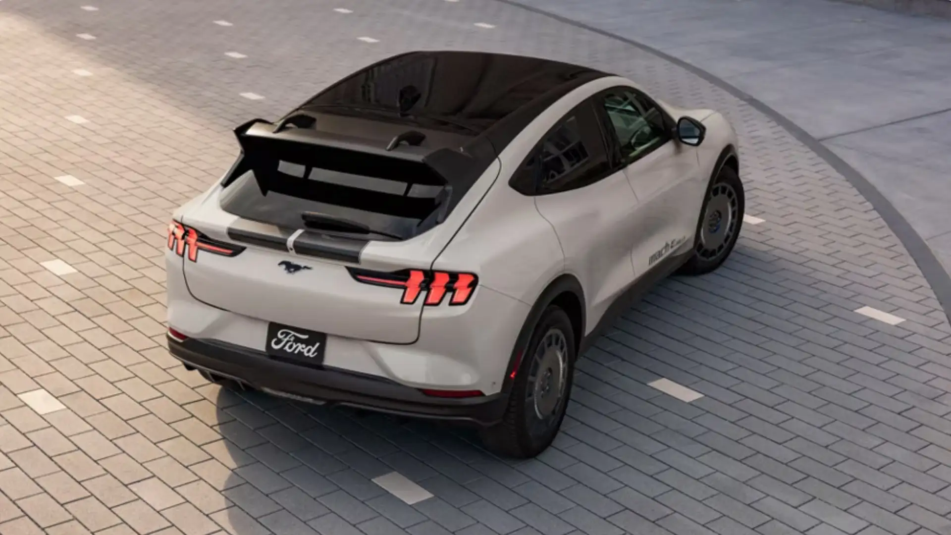 Rear view of a 2025 Ford Mustang Mach-E® showcasing its tri-bar LED taillights, black roof, and aerodynamic rear spoiler.