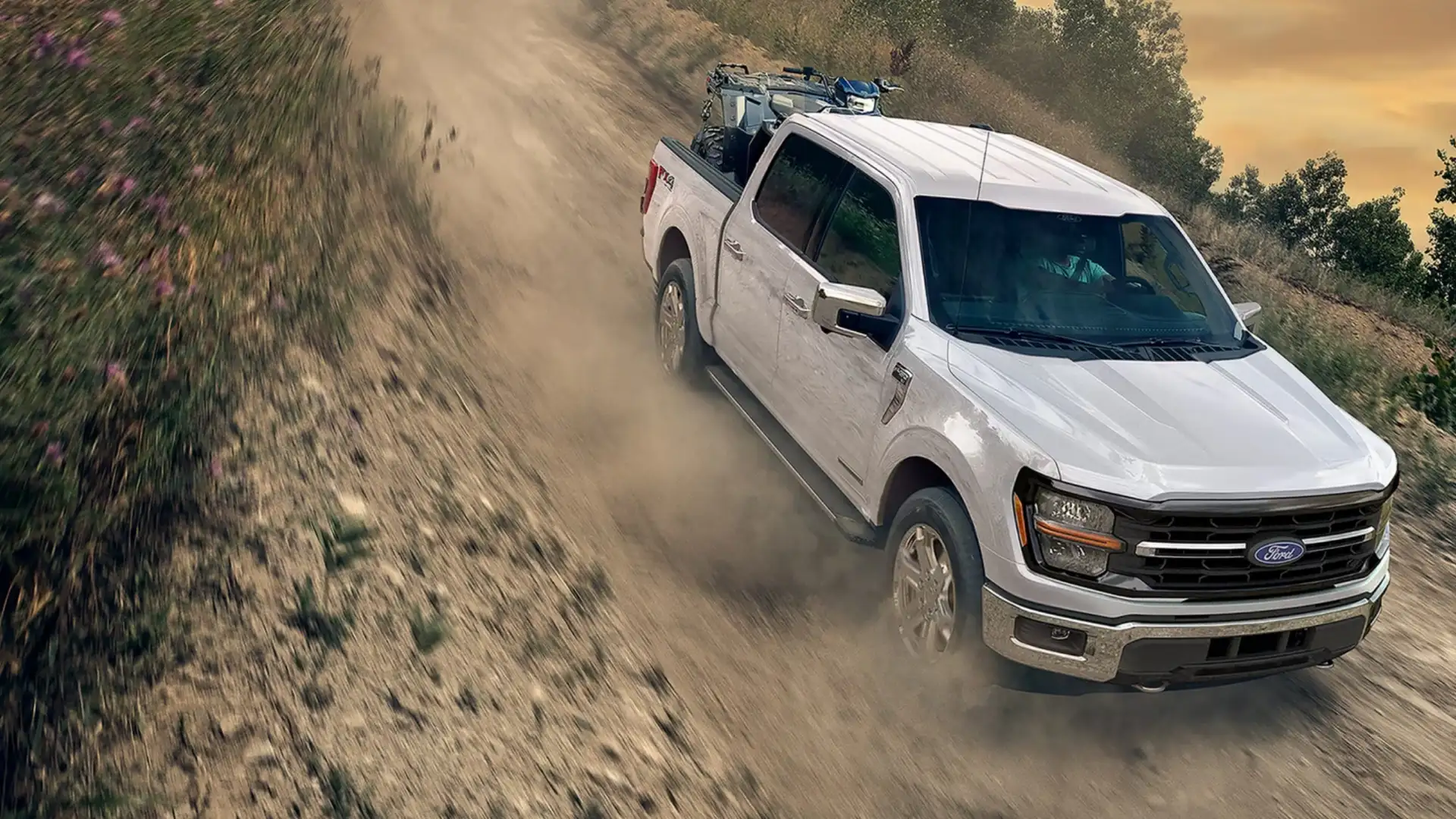 2025 Ford F-150® driving on a rugged trail, kicking up dust, showcasing its off-road capability and tough performance.