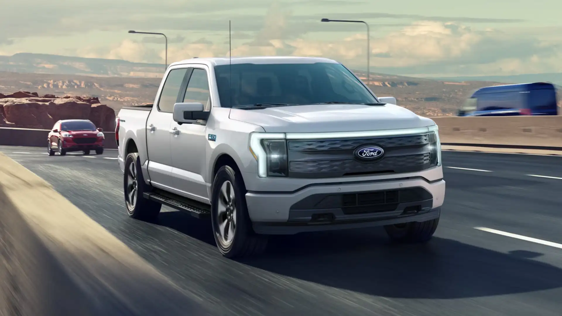 2025 Ford F-150® front three-quarter view in white driving on highway at speed.