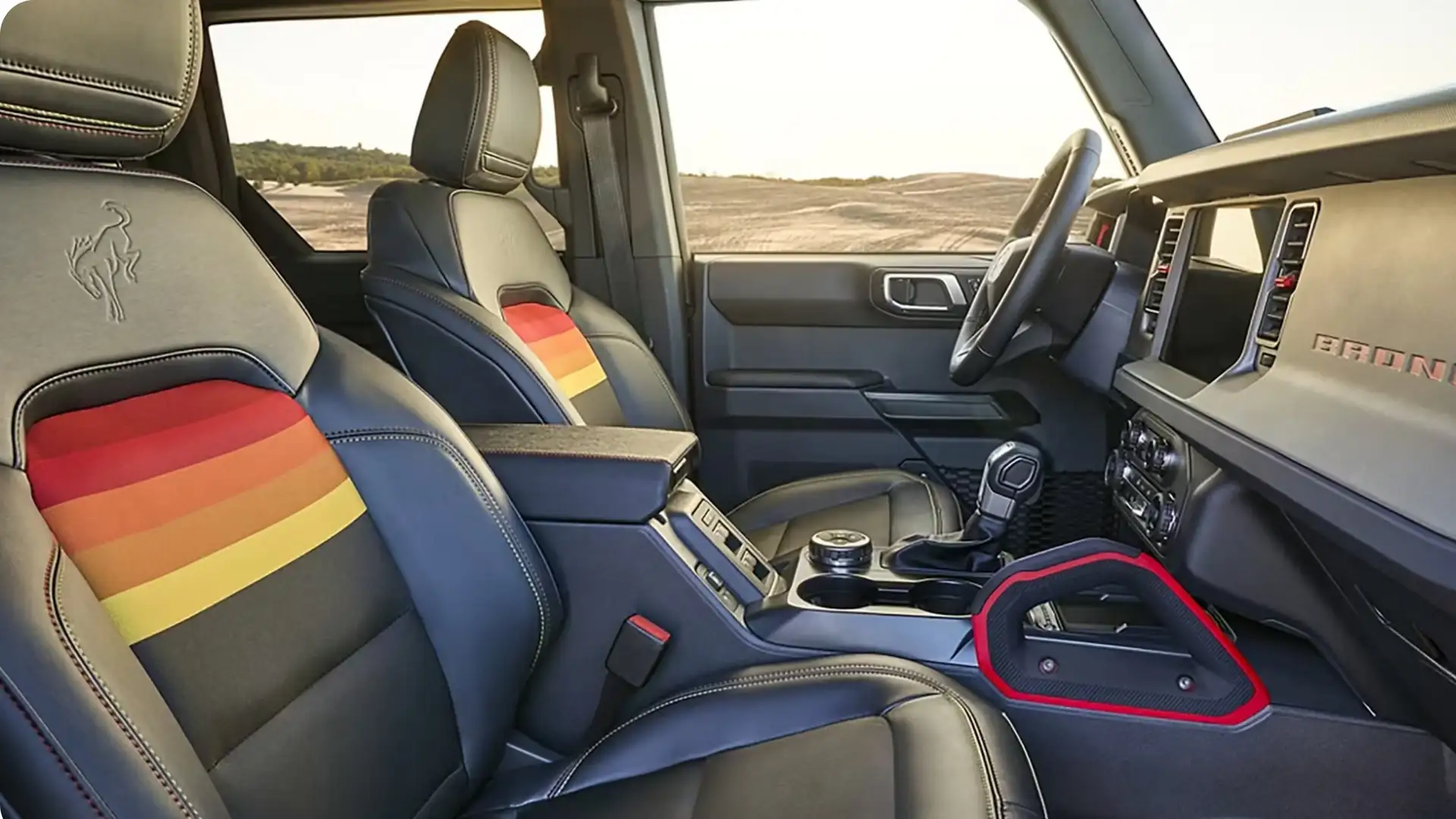 Interior of 2025 Ford Bronco® with black leather seats, rainbow stripe inserts, center console, and rugged off-road design details.