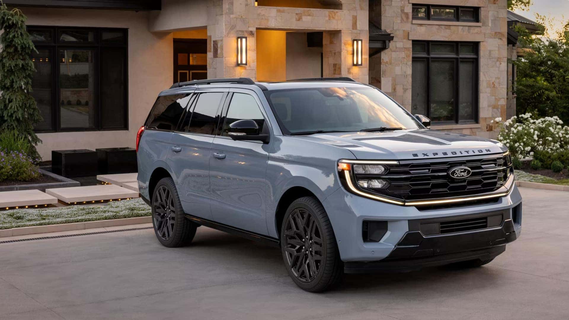 2026 Ford Expedition® in gray parked in a modern home driveway, front three-quarter view with LED headlights and black grille.