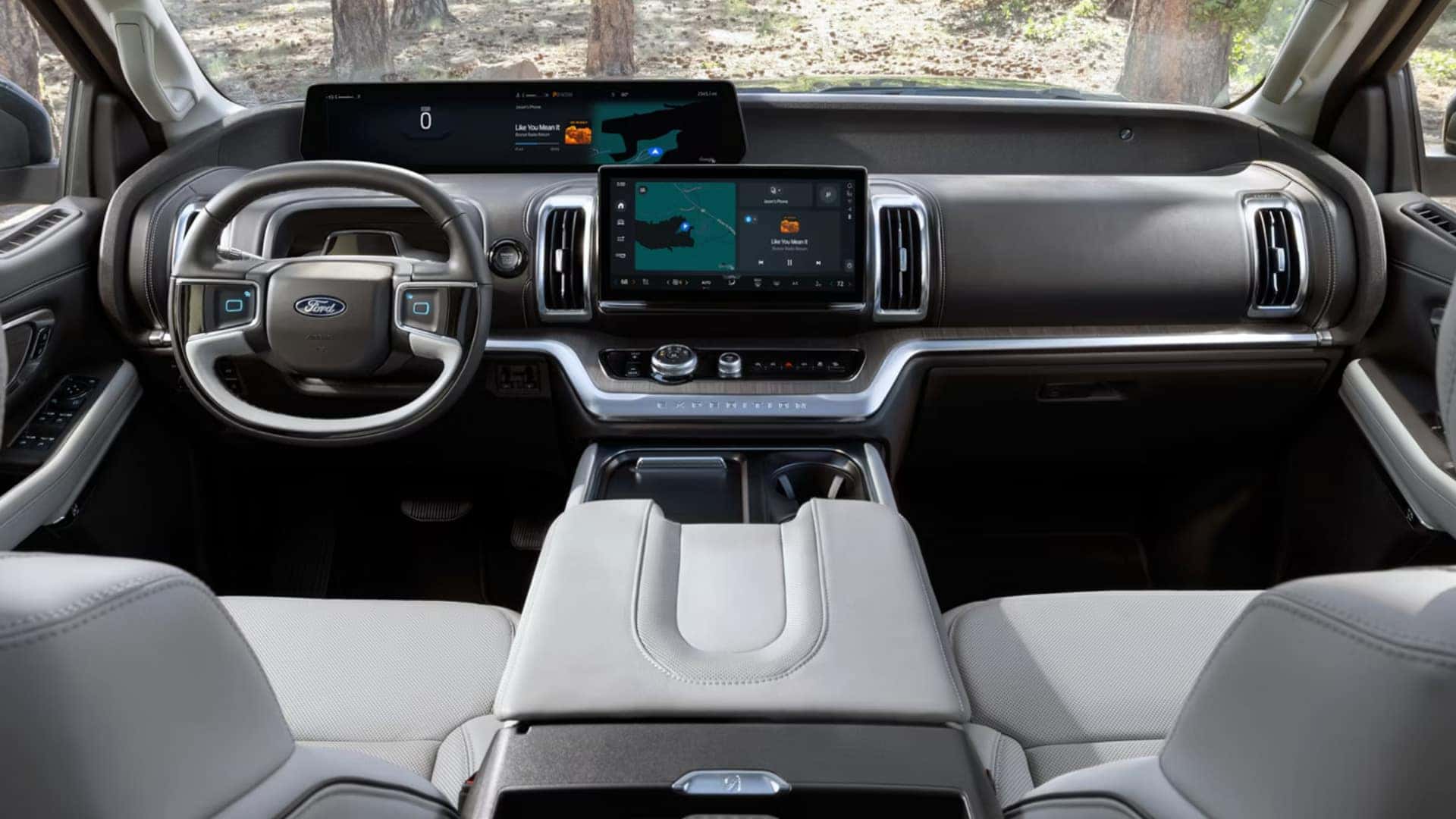 2026 Ford Expedition® interior cockpit view with Ford steering wheel, digital display screens, center touchscreen, and light-colored seats.