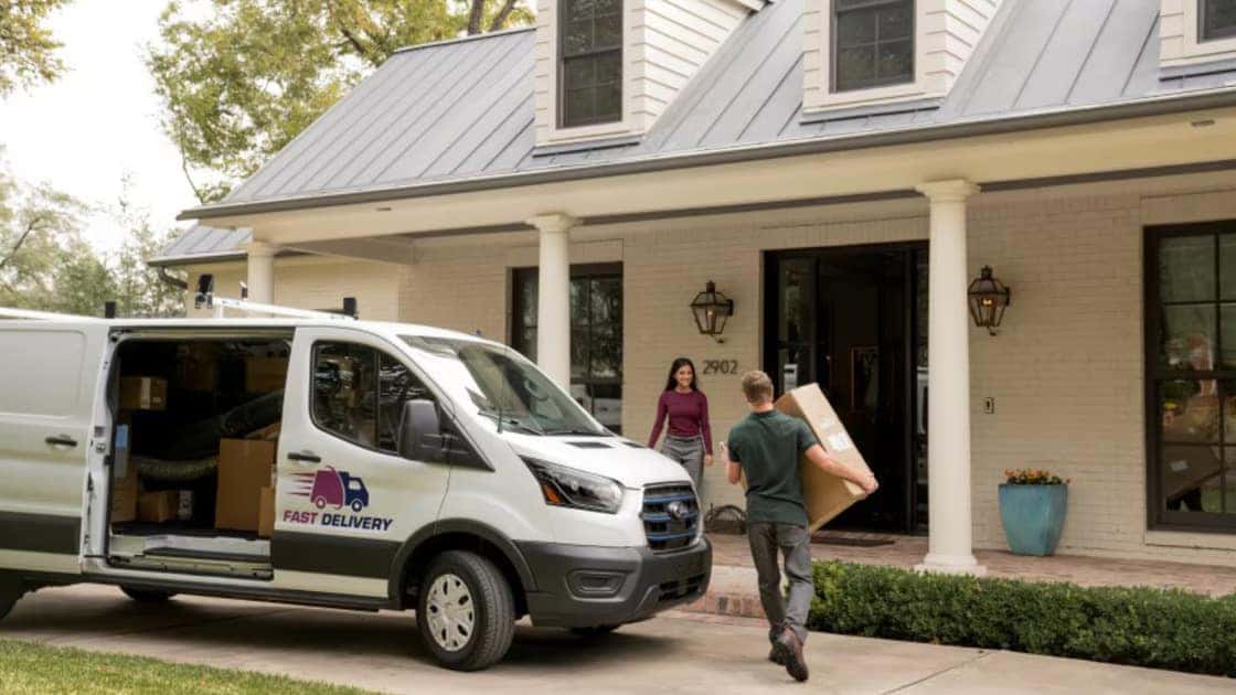 2026 Ford E-Transit™ delivery van parked at a home with a package delivery in progress.