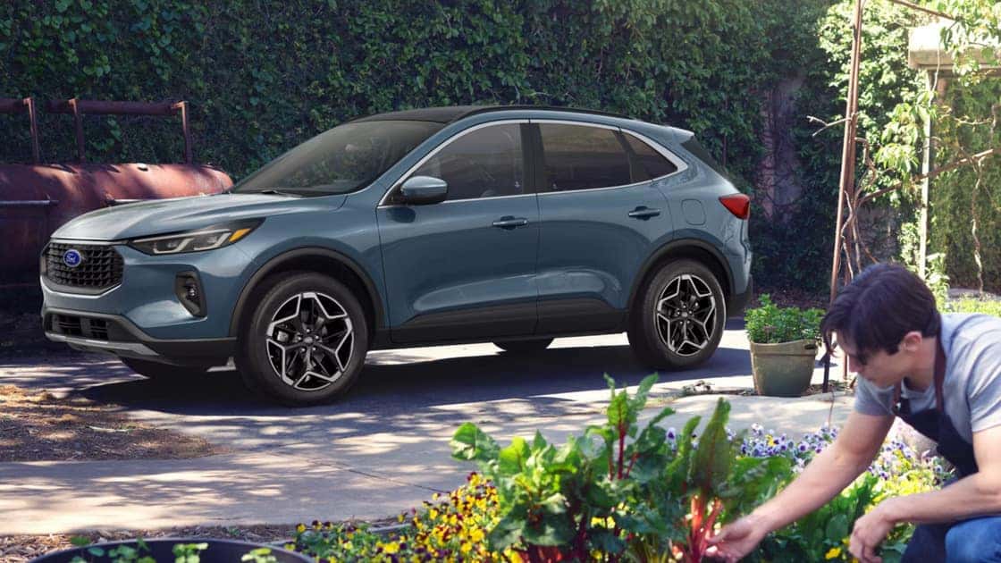 2026 Ford Escape® parked in a driveway beside a garden with a person working in the foreground.