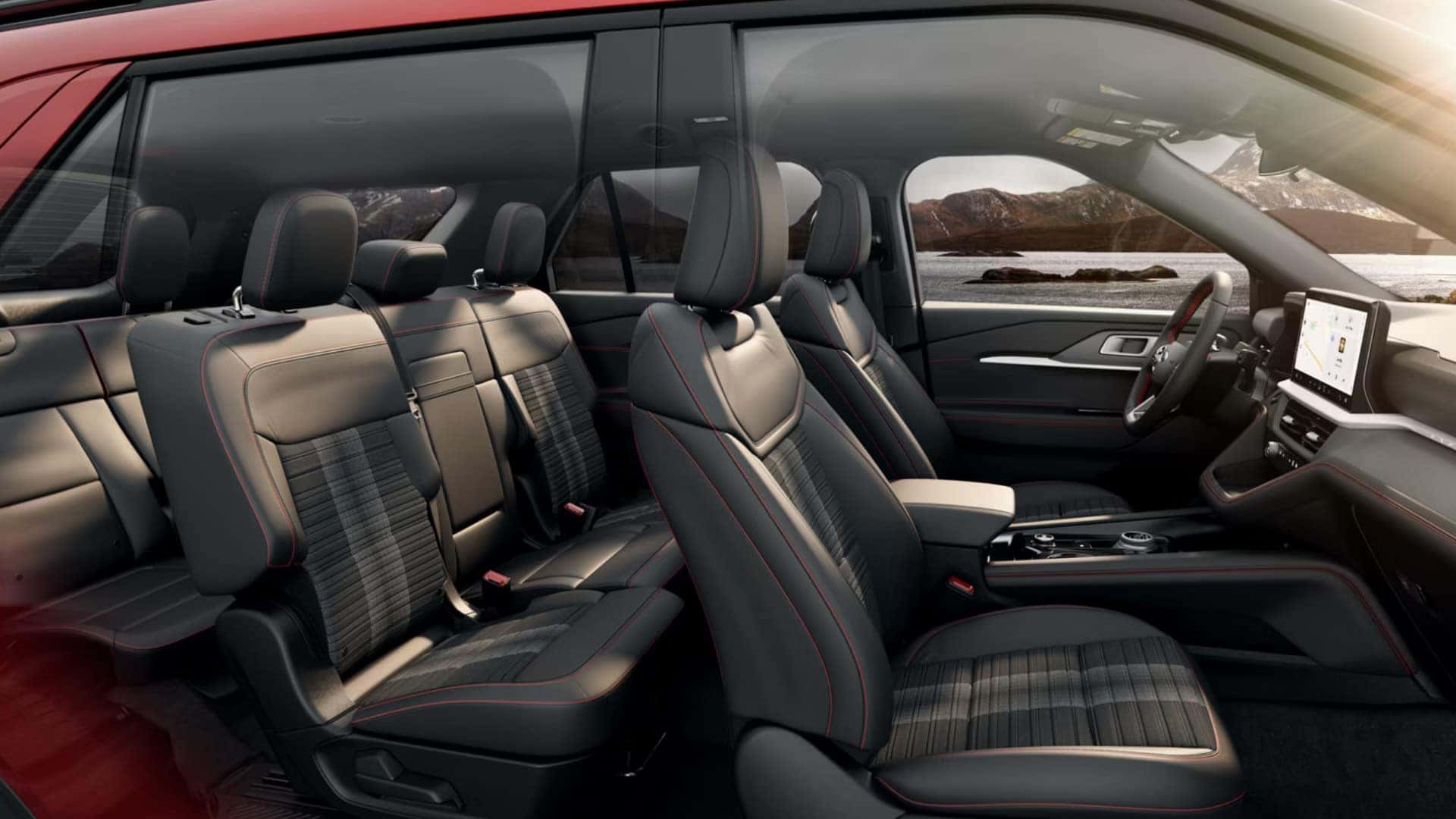 2026 Ford Explorer® interior front view showing steering wheel, touchscreen infotainment system, and coastal background through window.