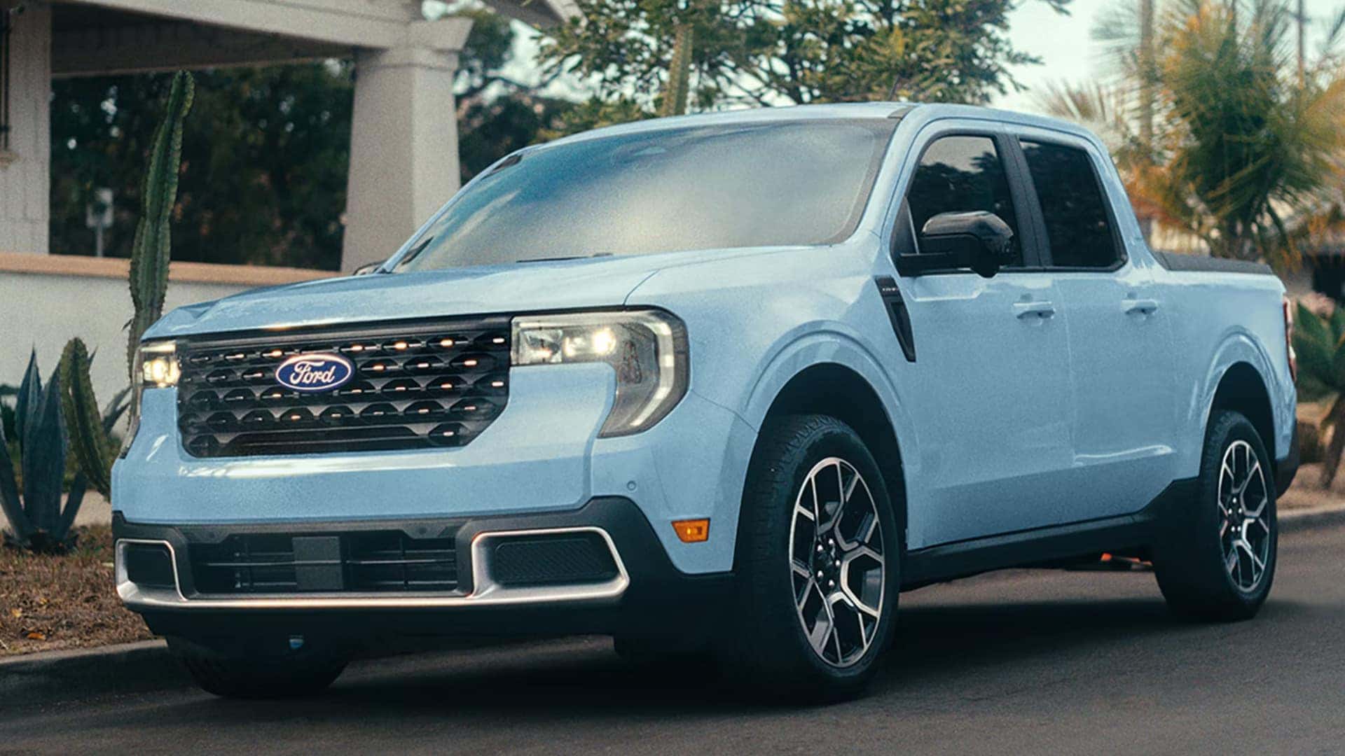 2026 Ford Maverick® light blue exterior parked outside a residential area, showing front grille, headlights, and side profile.