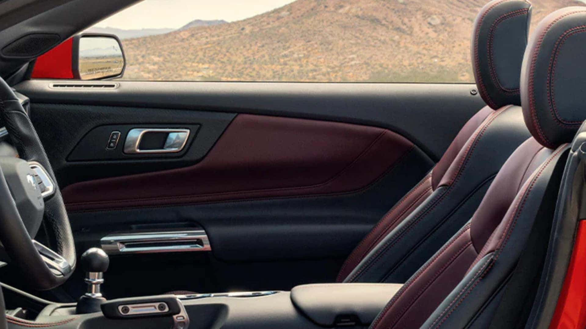 2026 Ford Mustang® interior passenger side view with red and black leather seats and door panel.