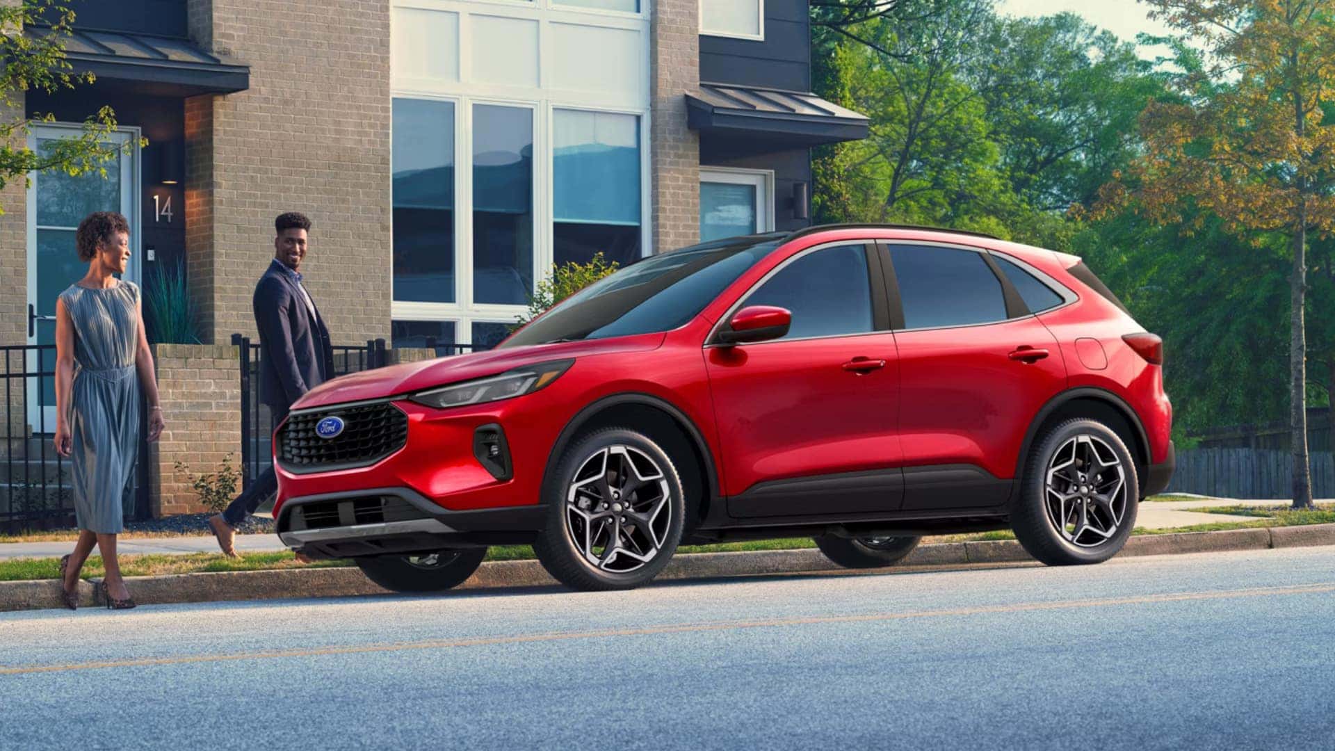 2026 Ford Escape® red SUV parked outside a modern home with sleek styling and sporty wheels.