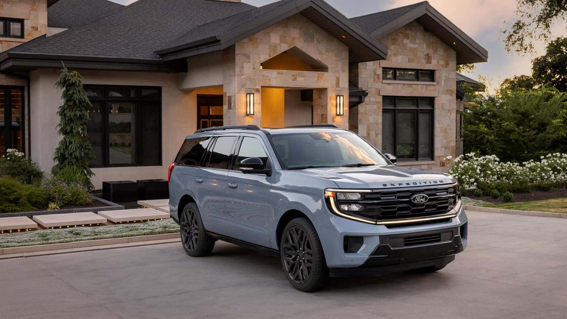 2026 Ford Expedition® SUV parked outside a luxury home with bold grille, black wheels, and LED lighting.