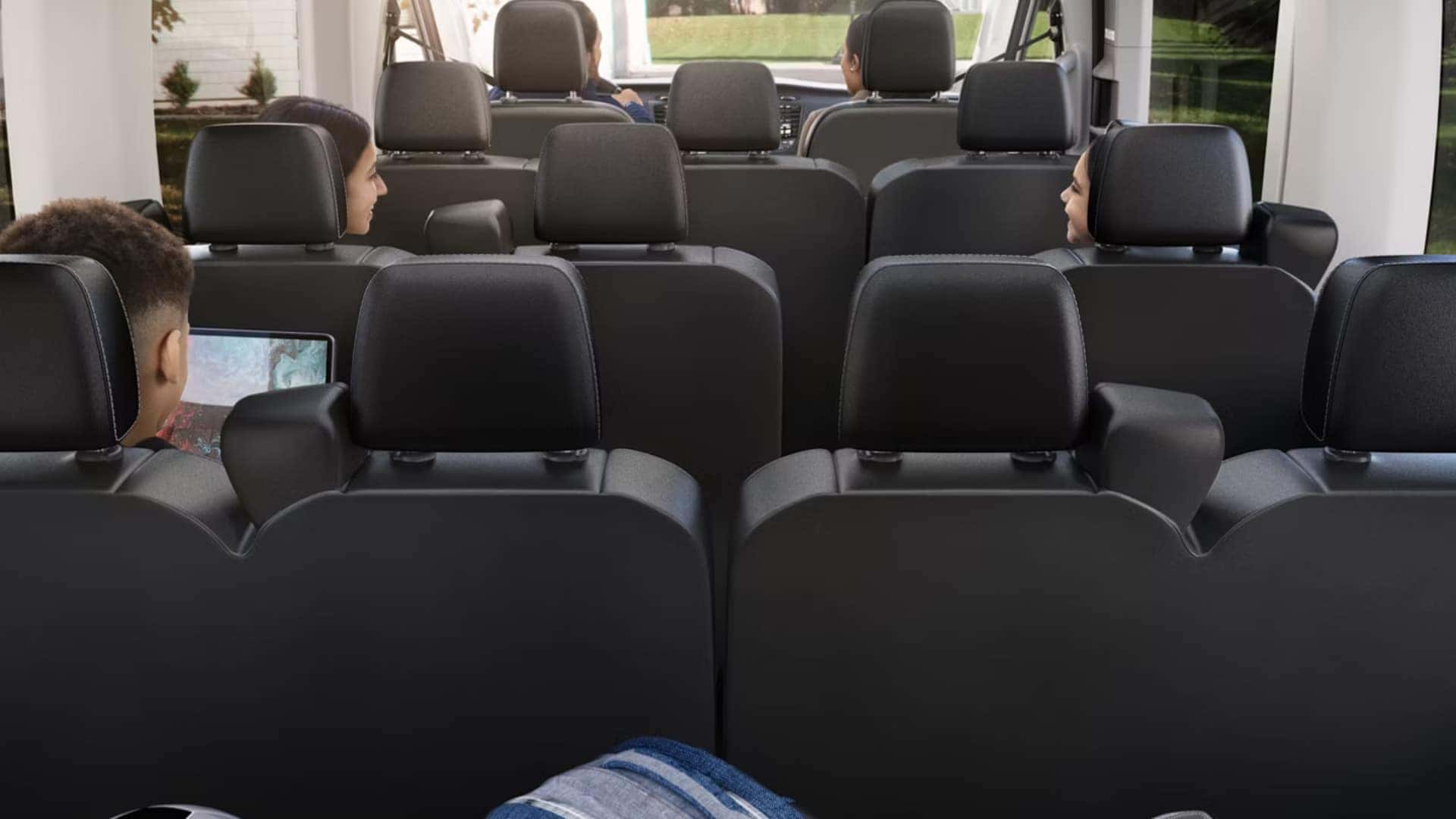 2026 Ford Transit® passenger van interior with multiple rows of seating and rear entertainment screen.