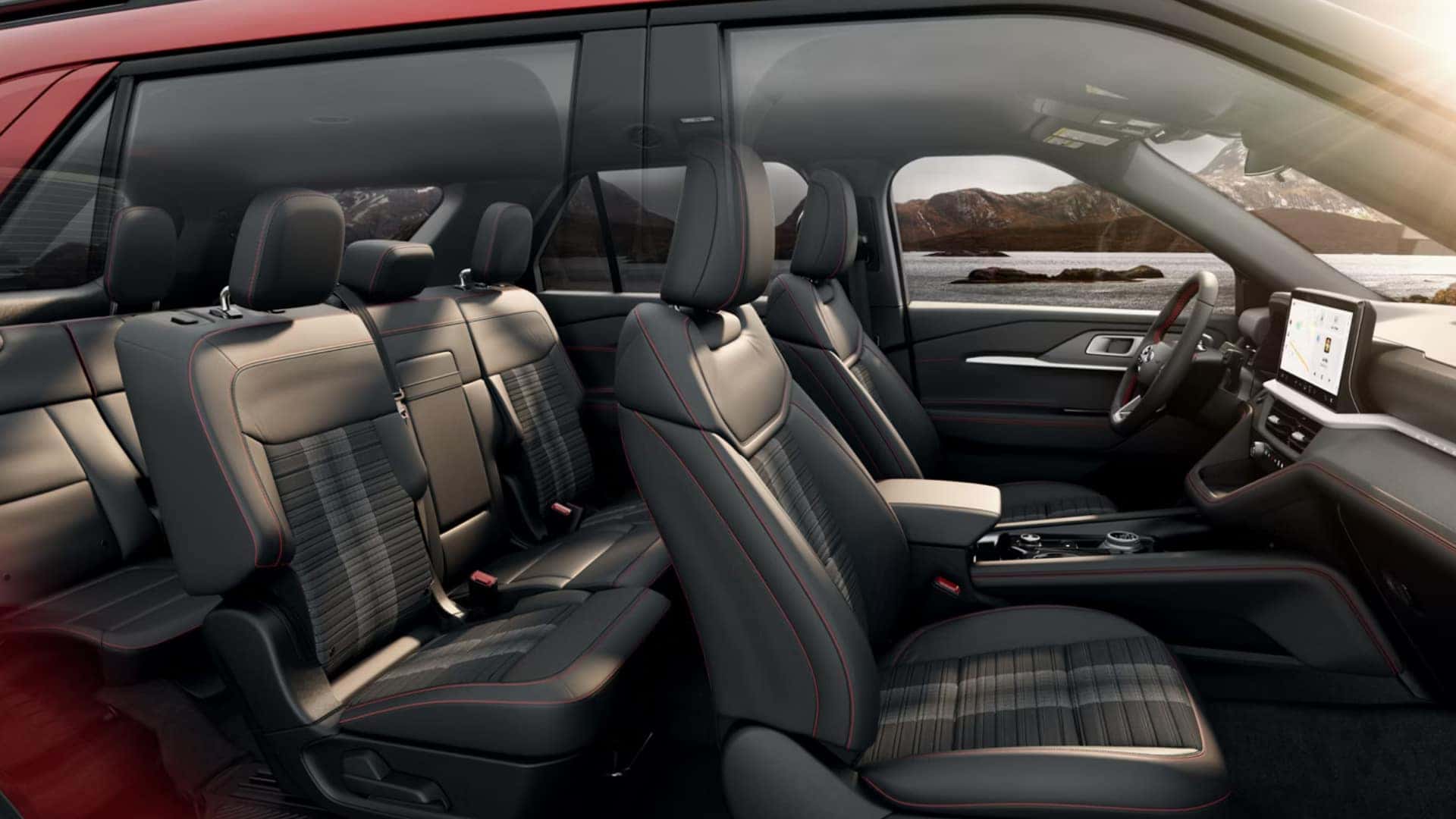 2026 Ford Explorer® interior seating with black upholstery, red stitching, three-row layout, and mountain view.