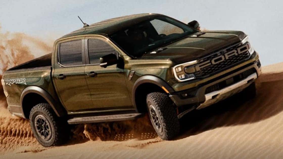 2025 Ford Ranger® Raptor driving through sand with off-road tires, wide stance, and desert-ready performance.